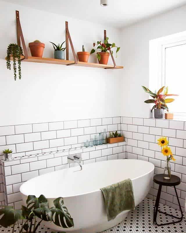 freestanding bathtub with white tile wall and wall shelf 