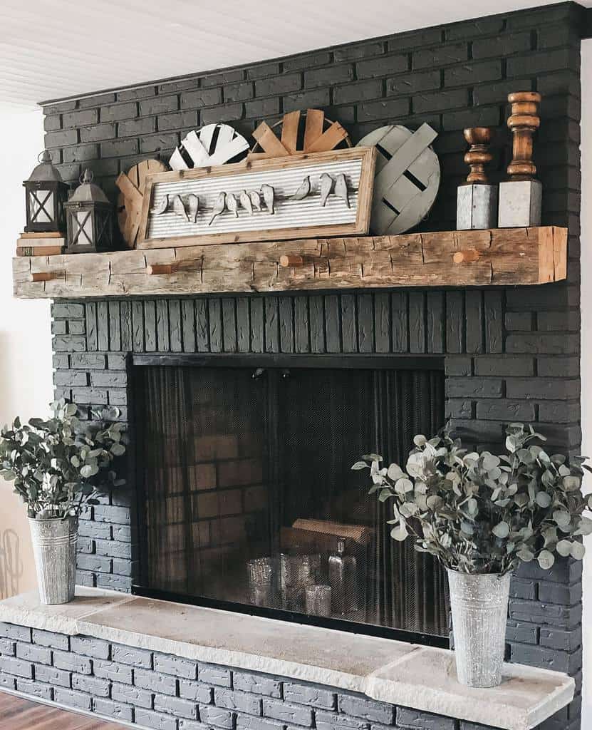 black brick fireplace wall wood mantle vase of flowers lanterns bird artwork 