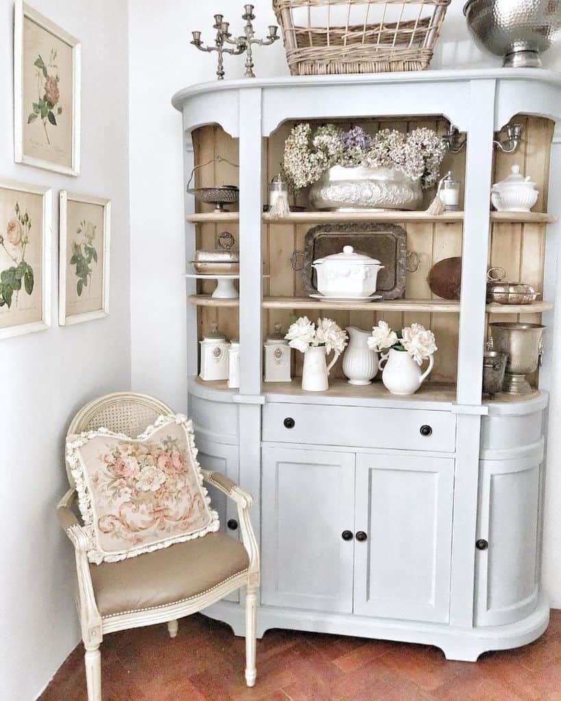 white cabinet with shelves porcelain jugs wicker chair candlestick