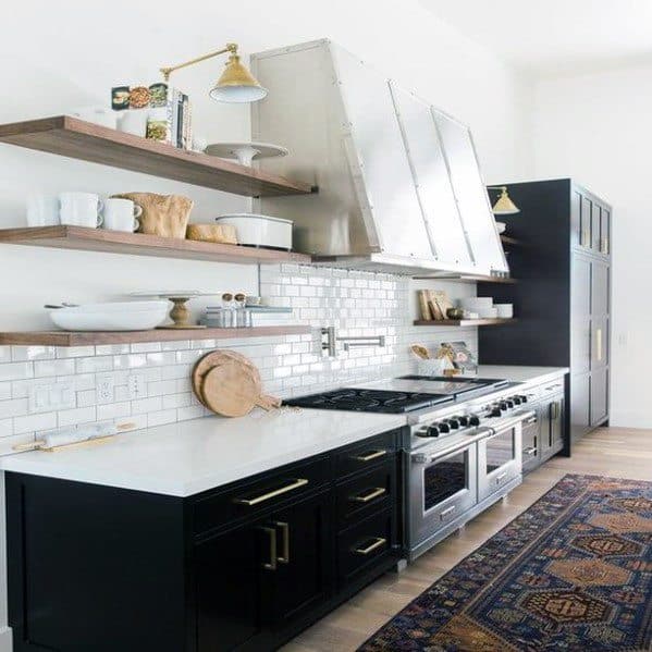 country kitchen with black cabinets wood wall shelves and dual ovens 