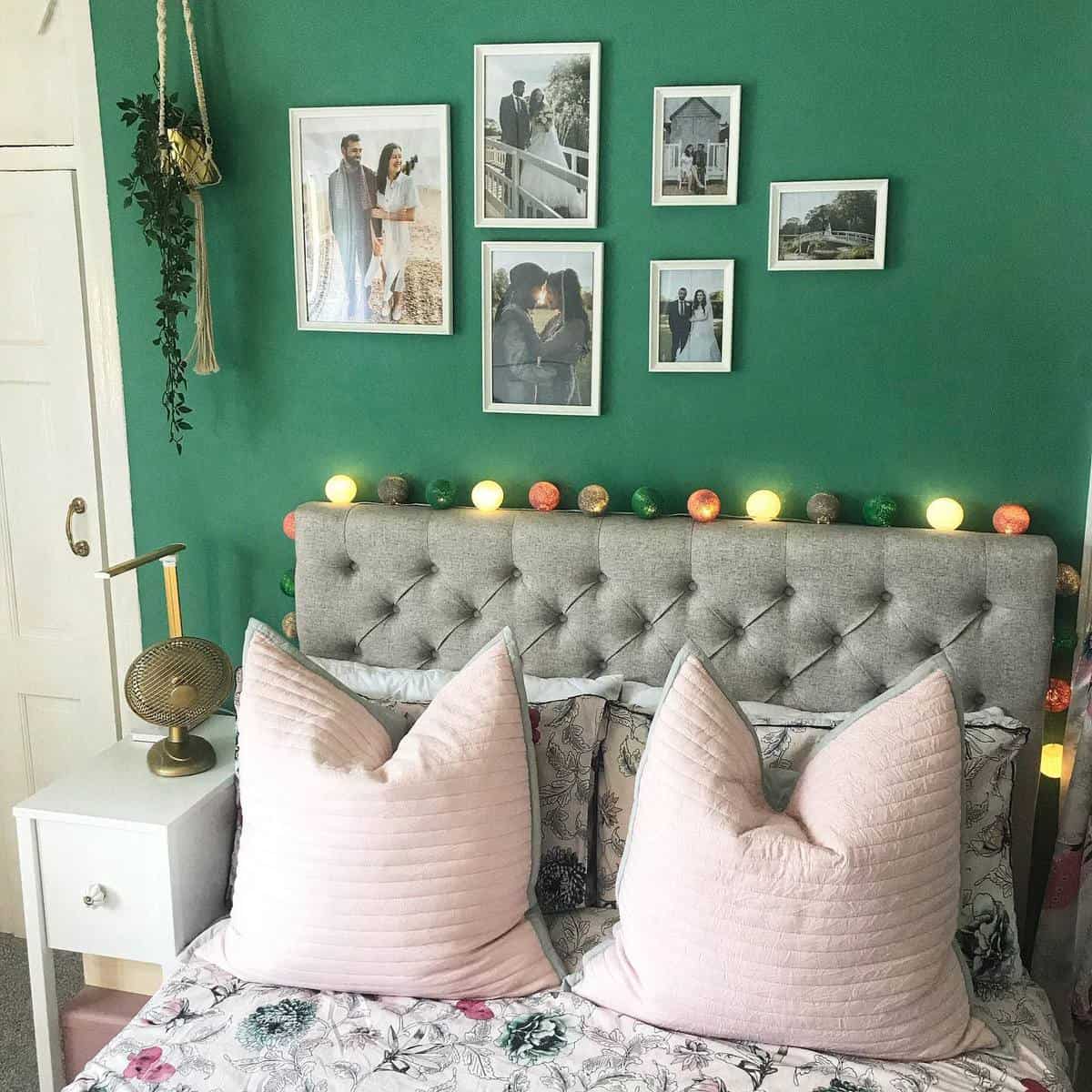 master bedroom green accent wall framed wedding photos string lights gray headboard 