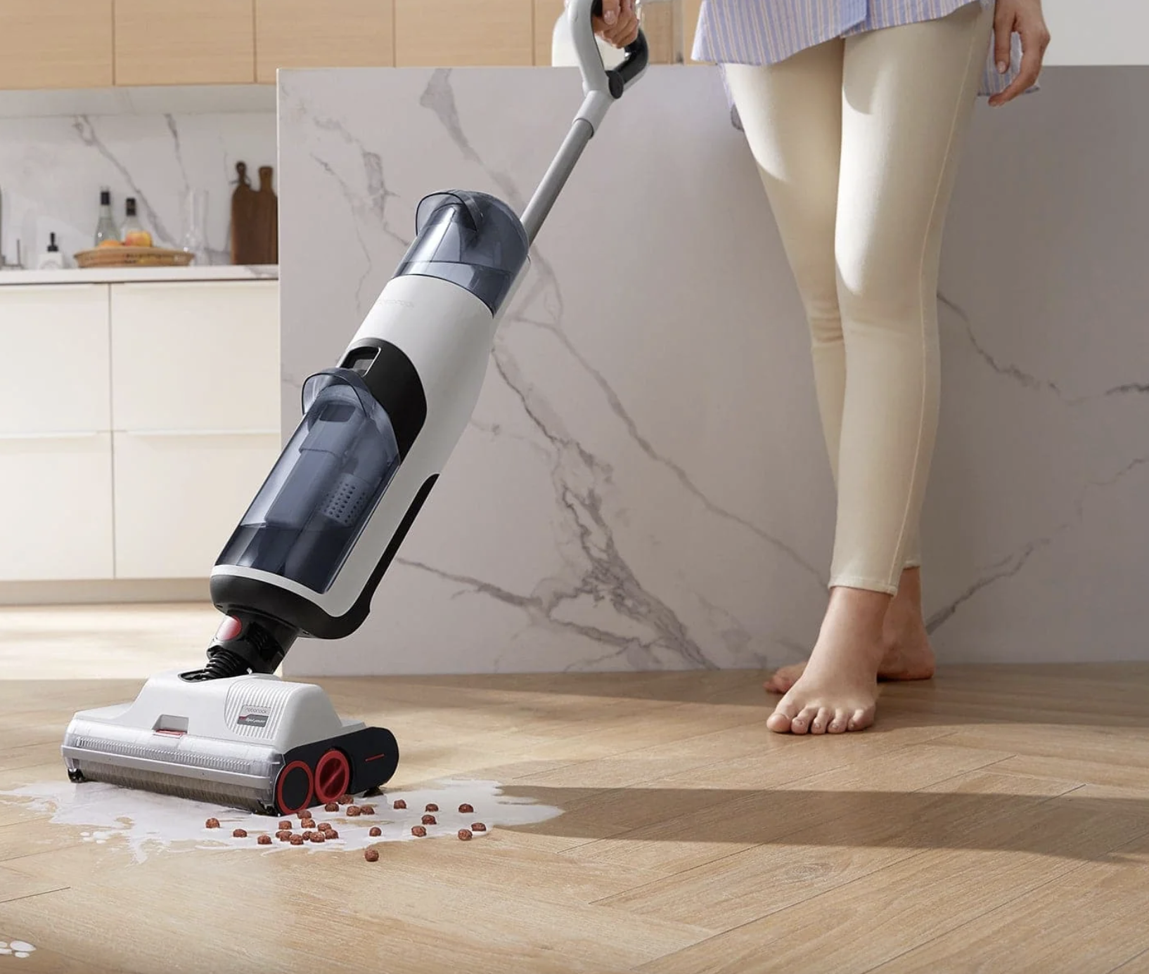 Roborock Original Dyad in Use on a Cereal Spill in a kitchen. A barefoot woman demonstrating use on a hardwood floor